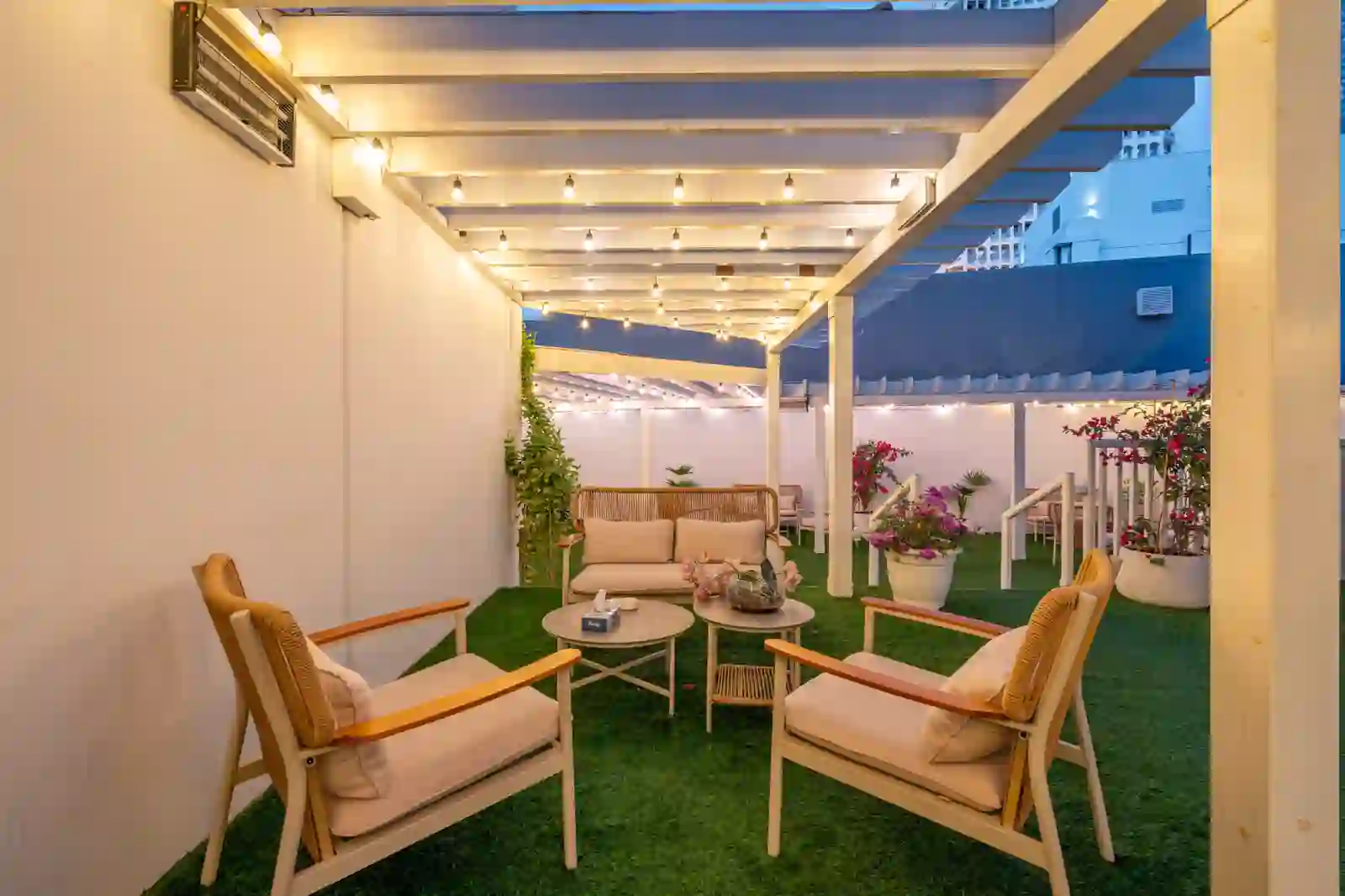 The Zentral outdoor terrace lounge with armchairs, string lights and greenery